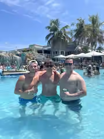 The three friends standing together in a crowded resort pool